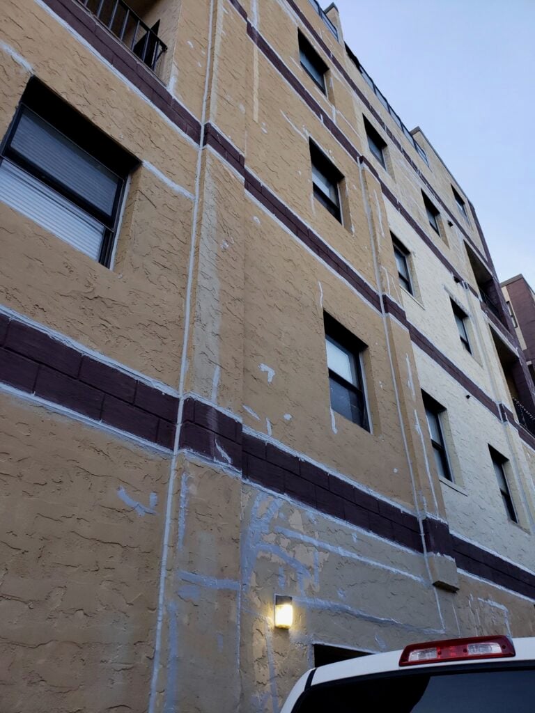 Control joint caulking and patched cracks on a textured stucco wall before coating