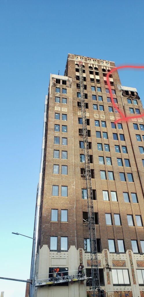 Brick high-rise with a mast climbing platform during masonry restoration