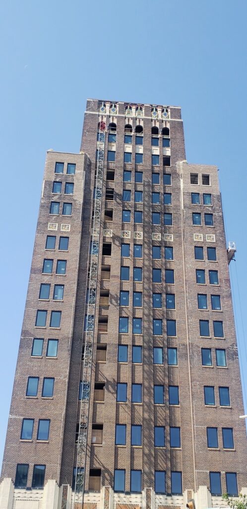 Brick building façade with a mast climber platform for masonry work