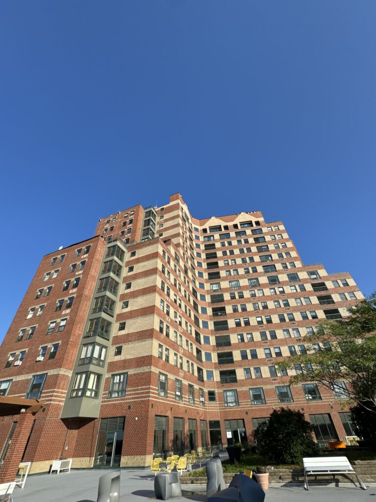 Brick high-rise with stepped rooflines against a blue sky