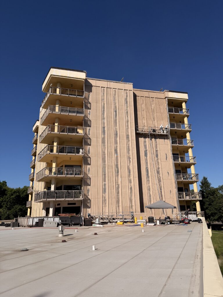 Precast and GFRC restoration in progress on a balcony tower, with a swing stage on the panels