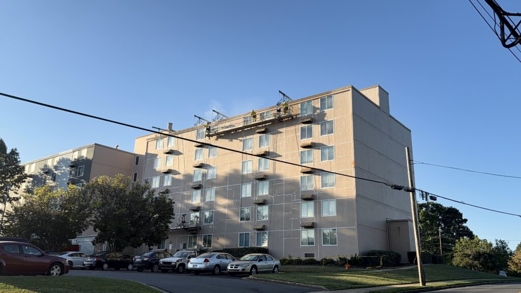 Mid-rise apartment building with a swing stage rigged at the roof for exterior work